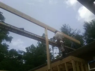 Carpenter setting a ridge beam over a new addition frame — Ice Dam Removal by Roofing Brothers in Westwood