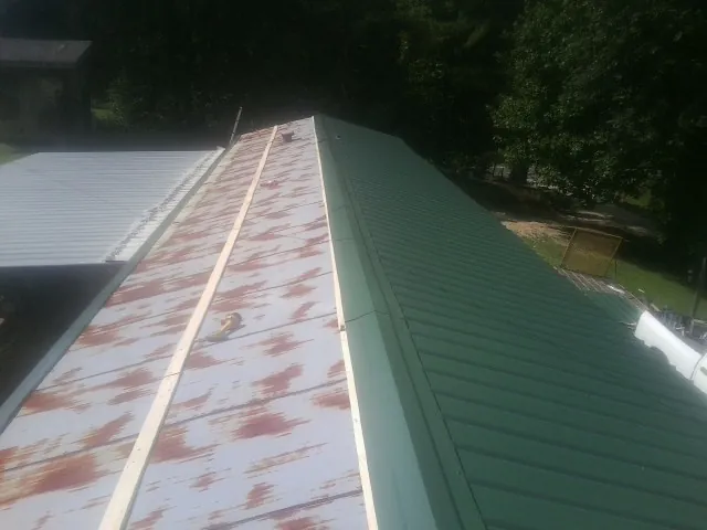 Old rusted panels beside newly installed green metal roofing — Wind Damage Roof Repair by Roofing Brothers in Westwood