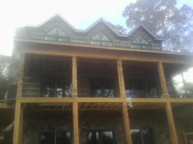 Dormers and porch framing on a large log home under construction — Roof Coating work by our crew in Westwood