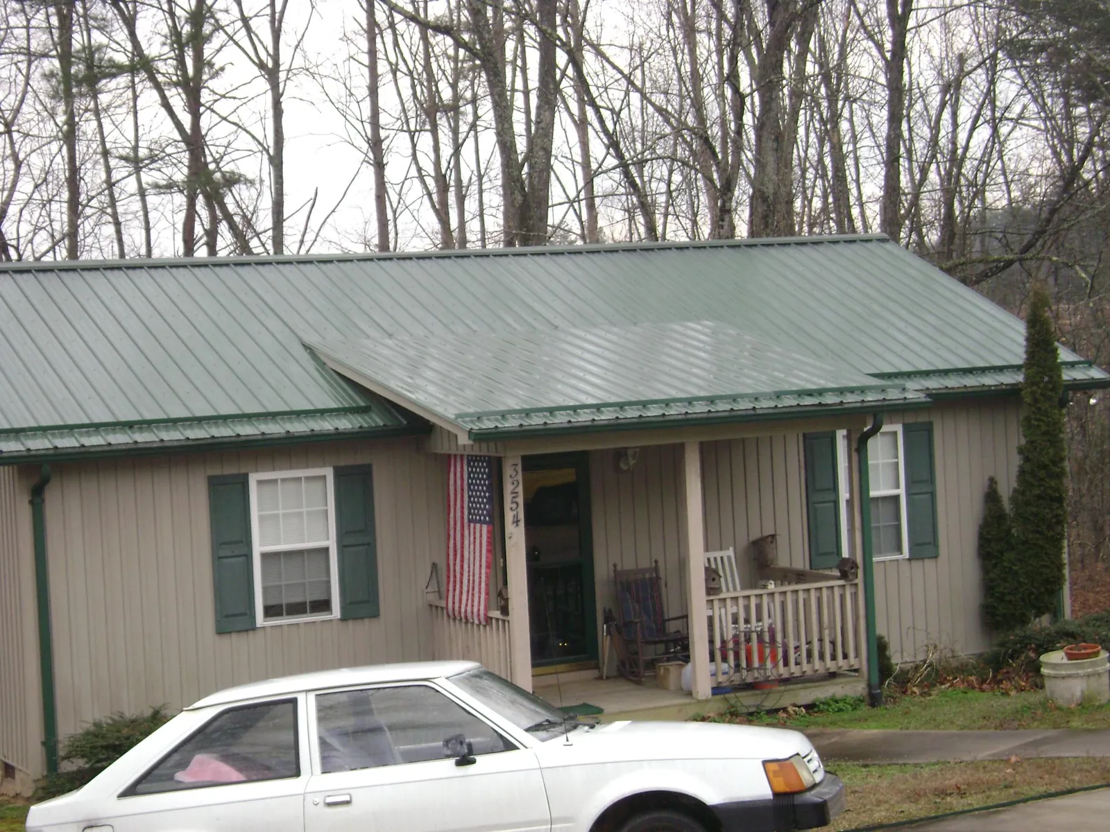 Green metal roof and front porch on a tan sided cottage in Westwood