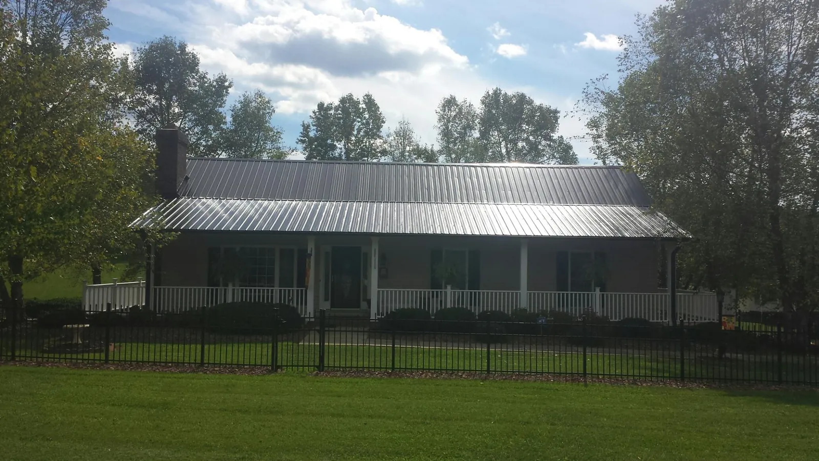 Gray metal roof on a brick ranch with a full width front porch — Gutter Guard Installation work by our crew in Westwood
